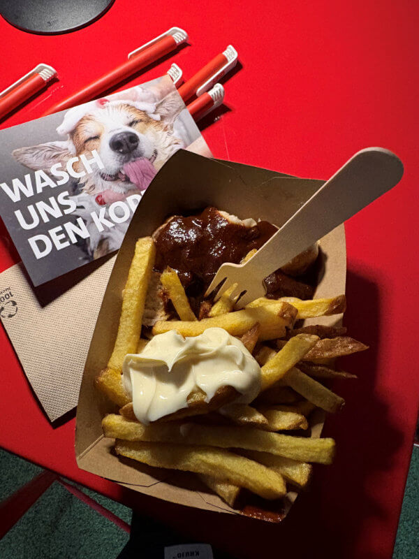 Currywurst-Pommes auf rotem Tisch
